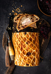 A luxurious Three Bird Wellington featuring layers of turkey, duck, and pheasant wrapped in golden puff pastry with herbed stuffing. Sliced to reveal the colourful cross-section and served on a rustic