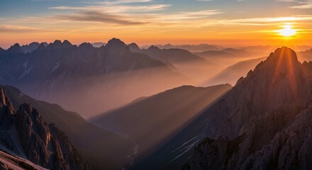 Panoramic view of a mountain range at sunrise. Golden sunbeams light up a hazy valley. Majestic alpine landscape for travel and adventure concepts