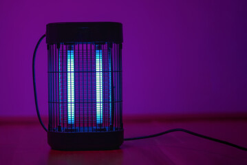 Electric insect killer lamp glowing in purple light