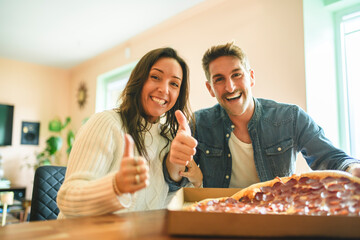 Loving couple shares tender moment in modern kitchen, enjoying pizza
