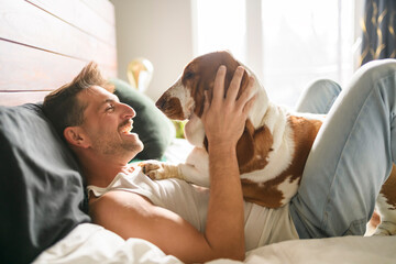 man and her Basset dog at home bed