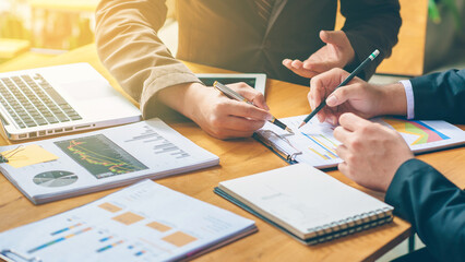 Professional team collaborating on financial charts and reports, planning business growth with a laptop and tablet for strategic decision making.