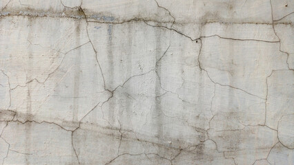 Close-up texture of a gray concrete wall with prominent cracks and scratches. Ideal background for grunge, industrial, decay, renovation, construction, and abstract concepts. Horizontal copy space.