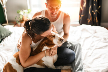 Couple and her Basset dog on bedroom having great time