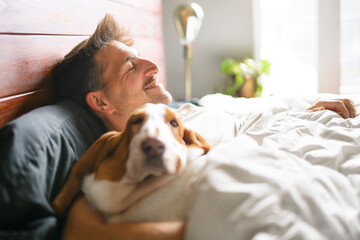 man and her Basset dog at home bed