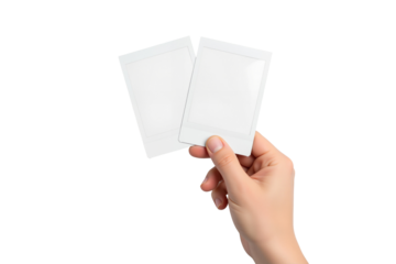 Hand holds two blank instant camera photo prints, perfect for showcasing memories or designs