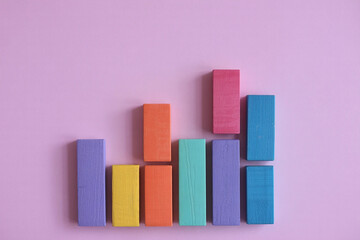 Colorful chalk sticks arranged in an upward trending bar graph on a purple background