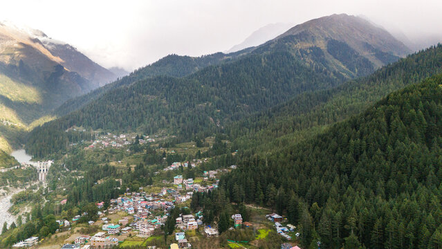 Pulga and Kalga villages in Parvati Valley, Himachal Pradesh, showing the lush green Fairy Forest with pine and deodar trees, snow-capped mountains, and clouds touching the peaks in autumn. - Powered by Adobe