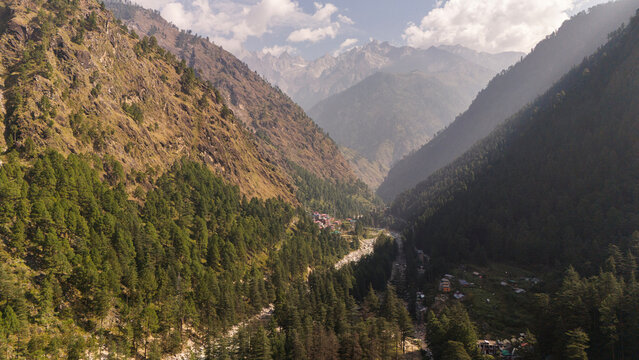 Layered green mountains in Parvati Valley, Kasol covered with dense pine and deodar trees, with soft mist drifting between the ridges, creating a serene and atmospheric Himalayan landscape.