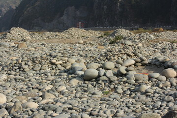 A wide, low-angle shot of a riverbed or dried floodplain covered densely with countless smooth,...