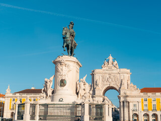 View of an equestrian statue atop a white marble pedestal, framed by a triumphal arch against a clear blue sky, evokes a sense of history and grandeur, Lisbon, Lisbon, Portugal.