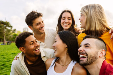 Diverse group of young friends having fun together outdoors in summer. Millennial student people laughing walking in city street enjoying day off. Youth community and friendship concept.