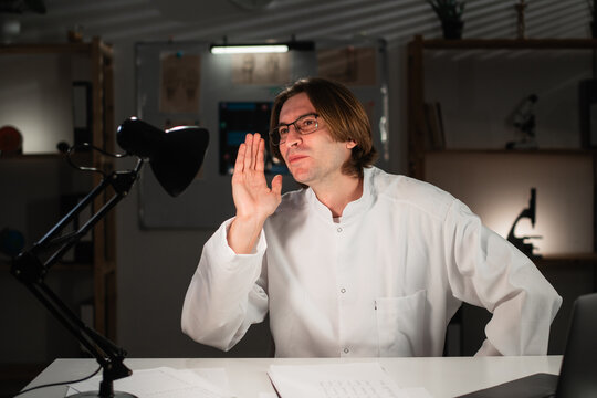 General practitioner doctor in eyeglasses posing screaming shouting yelling bawls looking at camera while working late night in hospital office