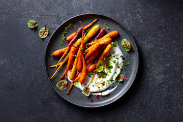 Simple Roasted Carrots with Yogurt and North African Spices. Dark grey background. Top view.