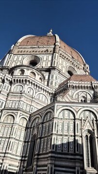 Vertical side view of Florence Cathedral eastern facade in warm morning light, highlighting detailed Renaissance architecture and textures in motion.