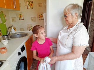 Grandmother and granddaughter making pancakes in the kitchen.