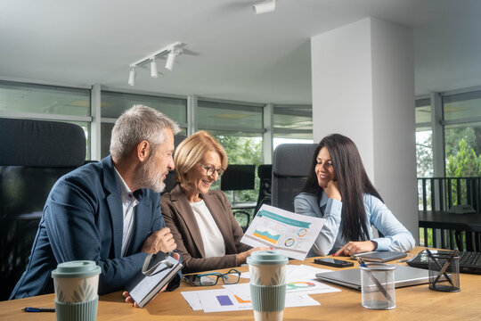 Casual meeting of smiling diverse business team analyzing financial data