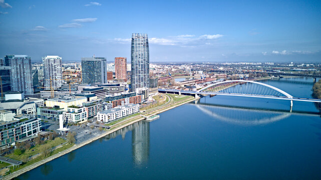 Aerial view of the modern skyline reflecting in the tranquil river, contrasted by the historic architecture and the arched bridge, Stare Mesto, Bratislavsky kraj, Slovakia. - Powered by Adobe