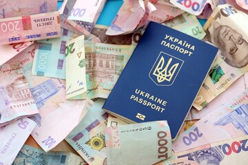 Ukrainian biometrical passport lies on big amount of different ukrainian hryvnia money bills