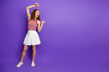 Young woman in red white striped top and white skirt celebrates joy against purple background