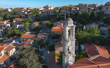 Aerial view capturing the picturesque Lofou village with traditional stone houses and a prominent white church bell tower. Limassol District, Cyprus