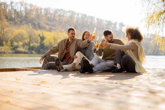Friends enjoying drinks by the serene lakeside in the golden glow of autumn - Powered by Adobe