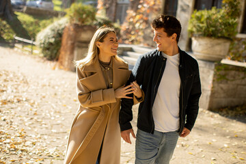 Young couple enjoys a sunny stroll through a leaf-strewn path on a fall day
