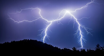Powerful lightning strike illuminates the night sky over a dark forest silhouette