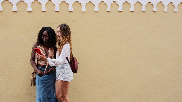 Diverse young women friends sharing smartphone content - Powered by Adobe