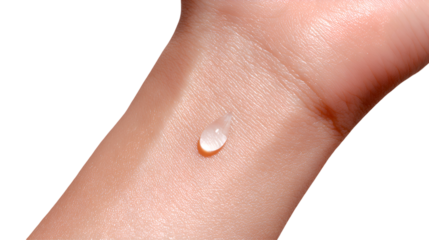 Extreme close-up of a small, clear teardrop-shaped liquid or serum drop on smooth human skin (wrist/hand), symbolizing product testing and hydration.