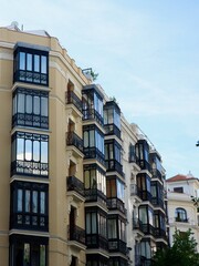 Obraz premium striking multi-story building adorned with glass balconies, reflecting the light of a clear blue sky in Madrid, Spain