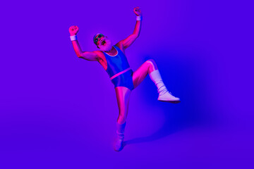 Energetic retro style male athlete leaps in blue and purple studio lights celebrating fitness joy and movement