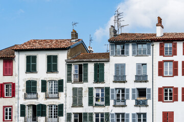 Colorful buildings with shutters in Bayonne, France, under a bright blue sky.