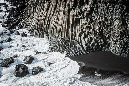 Basalt columns cliffs above black sand beach in Iceland