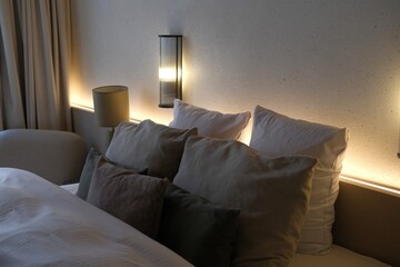 Cozy bedroom with double bed, comforter and pillows in hotel room or apartment. Interior design, vacation and relax. Comfortable space for sleep, home routine