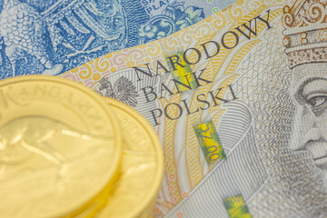 Złote monety na tle polskich banknotów