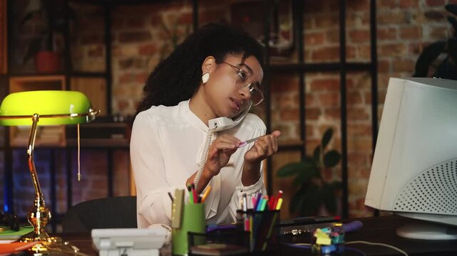 African American employee in retro clothes doing nails and talking on phone