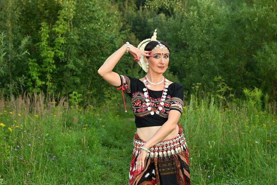 Indian female dancer in a beautiful costume on a green nature background in a park