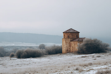 stone church stands majestically in snowcovered field under grey overcast sky