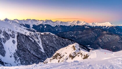 Snowy mountain range at sunset, with layers of peaks fading into the distance under a colorful sky