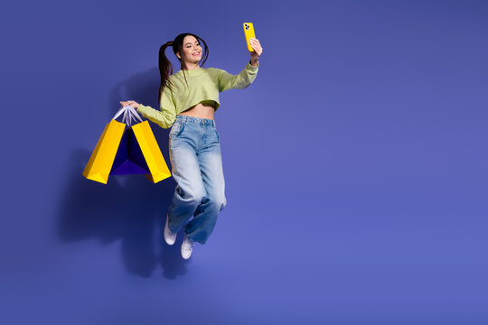 Young woman in trendy casual outfit holding shopping bags and smartphone on colorful background celebrating fashion - Powered by Adobe