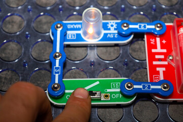 ​A close-up view demonstrates the process of building an electrical circuit using a children's construction set, where a switch is being turned on. © Олег Струс