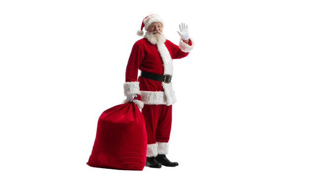 Santa claus in a red suit with a black belt waving while holding a large red sack of gifts on a solid white background cutout