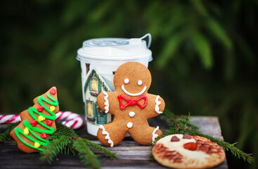 Cute Gingerbreadman and Shortbread Owl cookies for Christmas and cup of coffee on outdoor fir-tree background