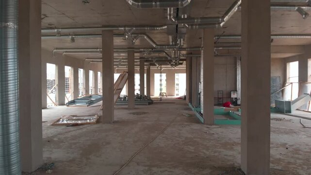 The interior of a building under construction. The camera is moving inside the building. Construction site.