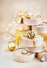 Christmas or New year round kraft gift boxes, gold holiday balls on a bokeh background of twinkling party lights of garland
