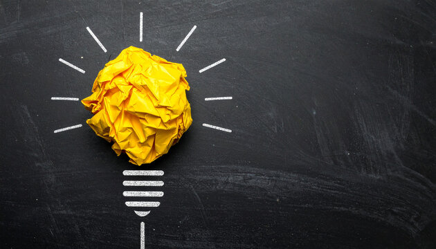 Crumpled yellow paper shaped like lightbulb on blackboard background, innovation and business ideas - Powered by Adobe