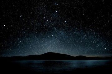 Starry night sky over a dark mountain landscape
