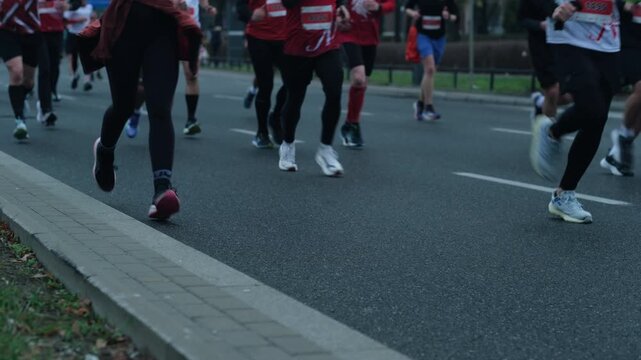 Runner's legs jogging on asphalt road, low angle shot
