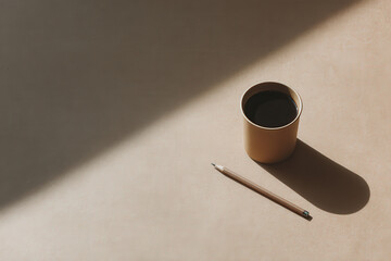 pencil rests on piece of kraft paper bathed in warm stripe of sunlight